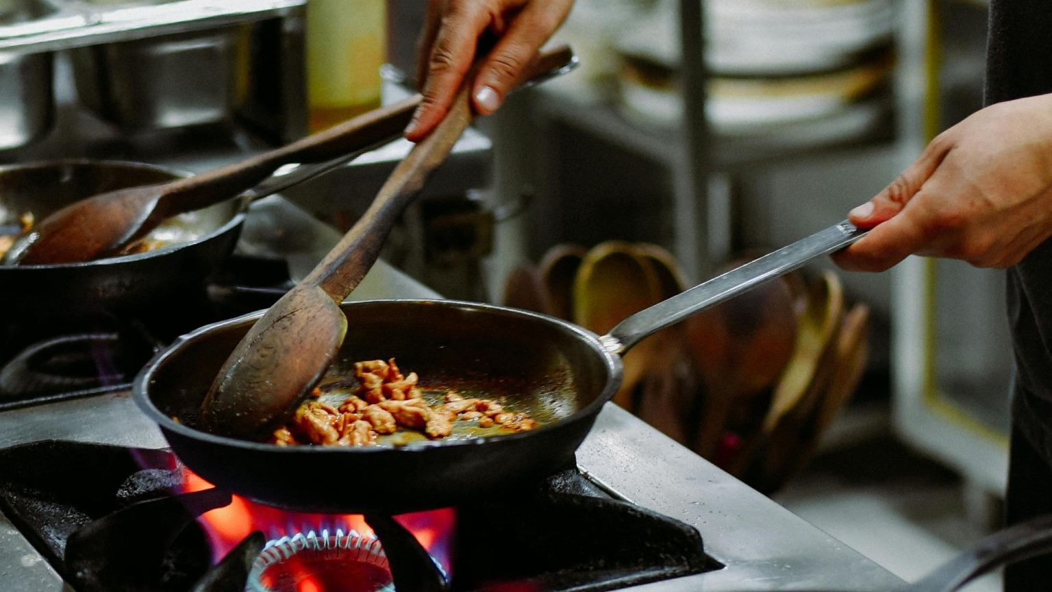 Une poêle à frire avec des Rojões à Moda do Minho grésillants, un plat traditionnel portugais composé de dés de porc, de tripes enfarinées, de chorizo, de foie et de sang.