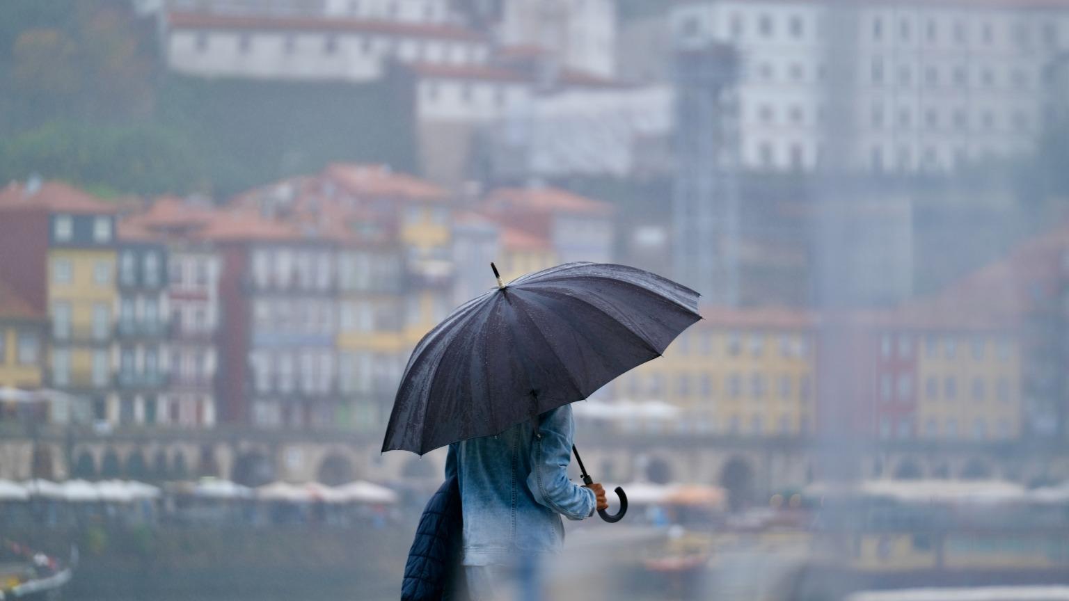 Persona disfrutando de un día lluvioso en Oporto, explorando lugares culturales con un paraguas