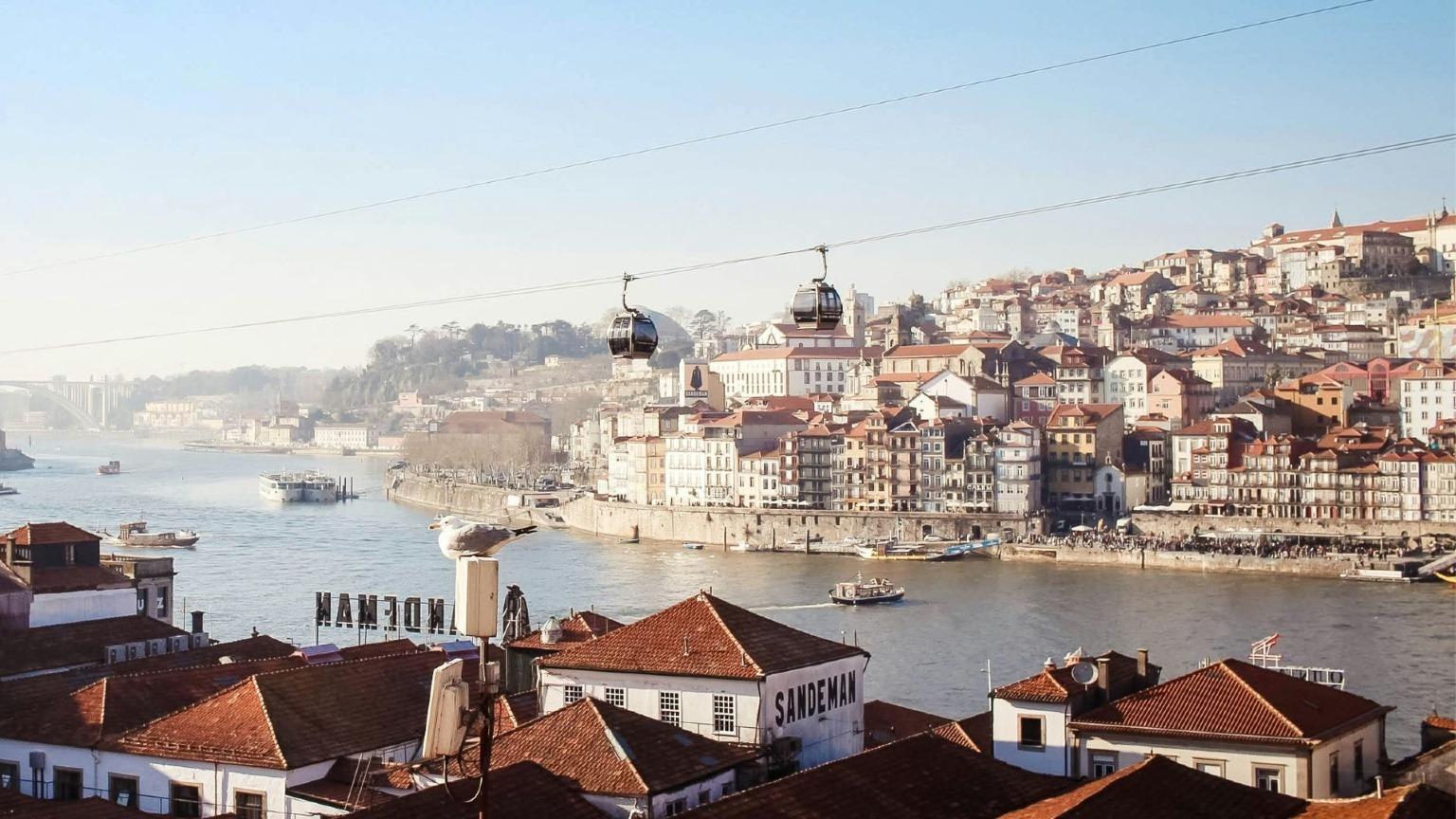 Uma vista panorâmica de Gaia mostra o teleférico, as caves, o rio Douro e a linha do horizonte do Porto.