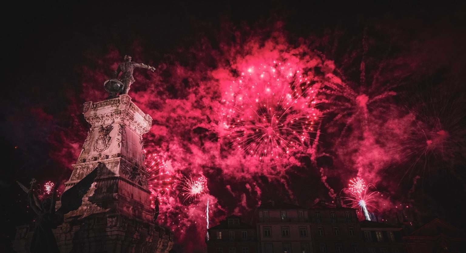 Vibrant fireworks lighting up the sky and reflecting on the River Douro, celebrating São João festivity in Porto.