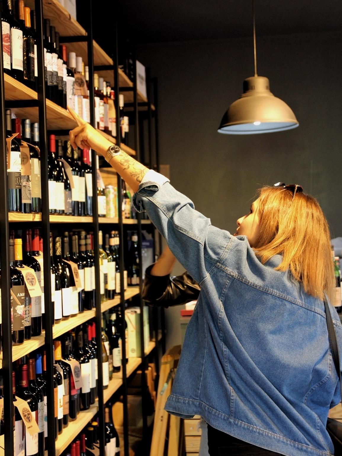 A woman explores a charming Porto wine shop, immersed in the rich tradition of local flavors and unique selections