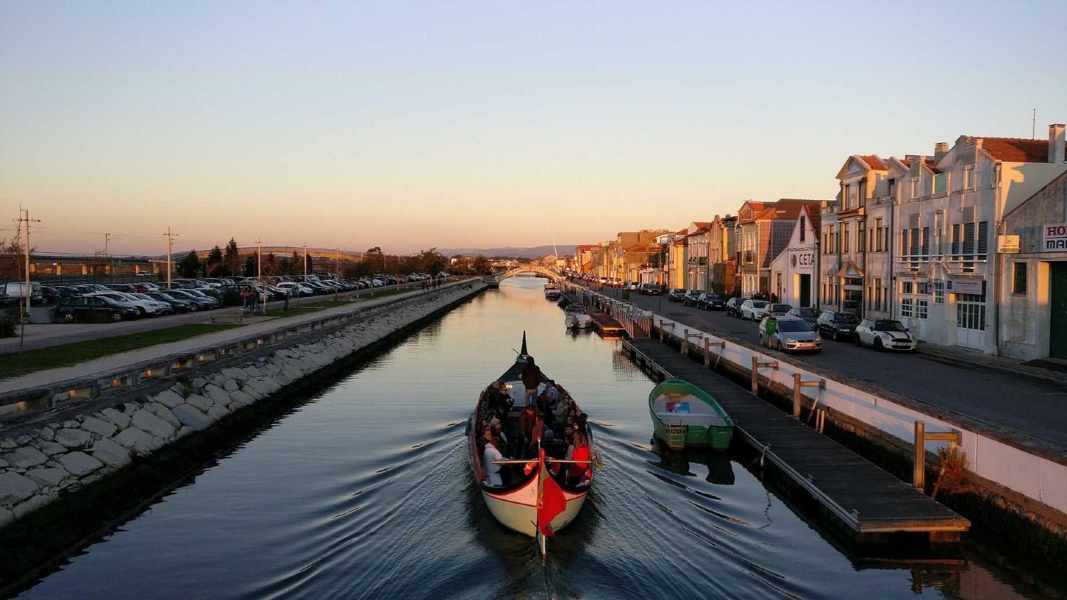 A traditional moliceiro boat floating on Aveiro's canal, with colorful buildings in the background.