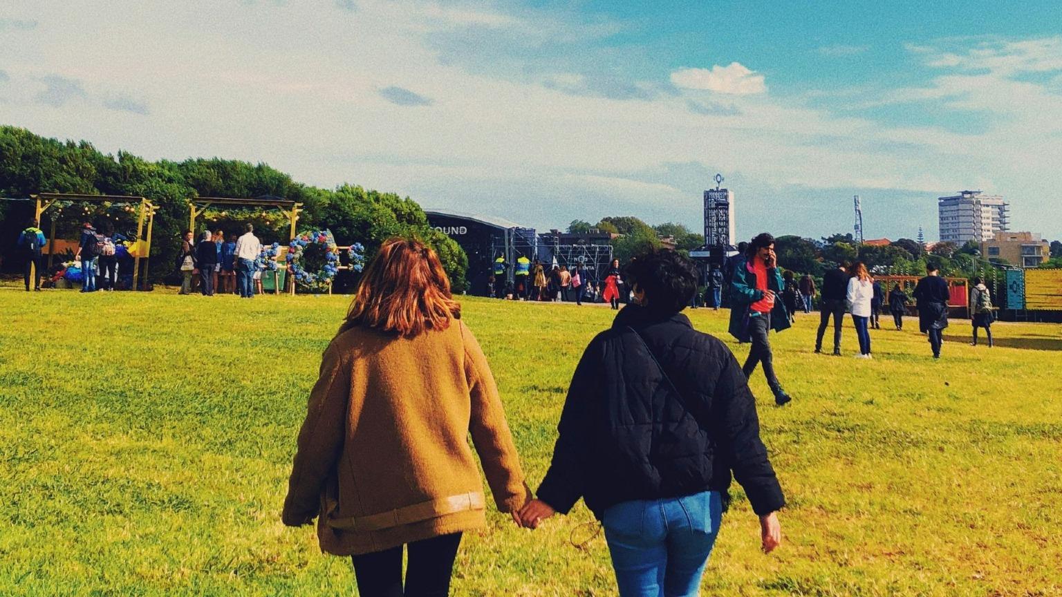 Festival-goers walk across the grassy fields of Primavera Sound in Porto during the day, enjoying the relaxed atmosphere and exploring various attractions.