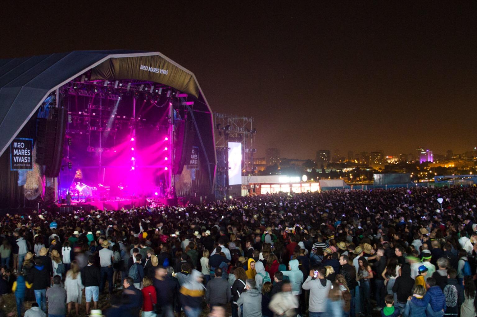 Atuação ao vivo em palco durante o Festival Marés Vivas perto do Porto, com uma multidão a apreciar a música.