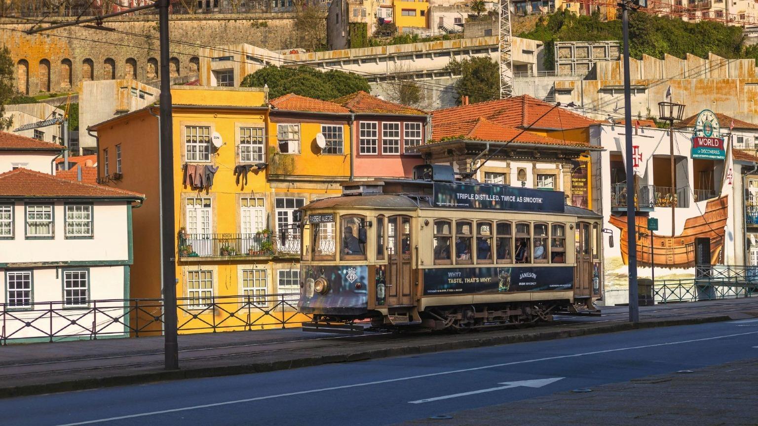 The iconic historic Tram number 1 traverses through Porto's charming historic area, surrounded by colorful buildings.