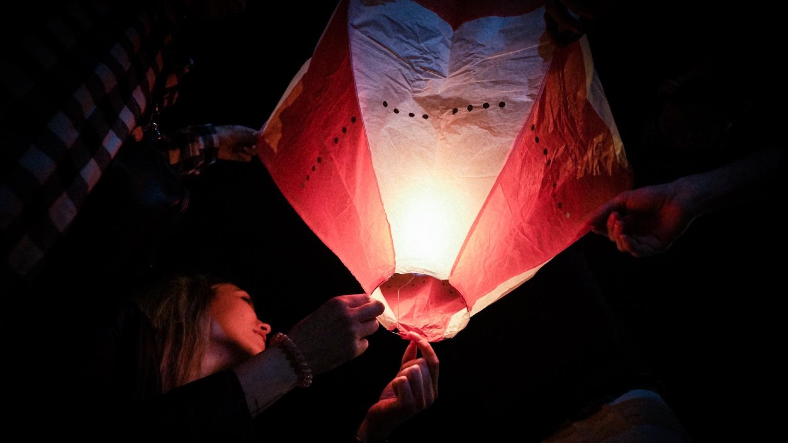 A brightly colored hot air balloon floating in the night sky, part of the São João festivities in Porto.