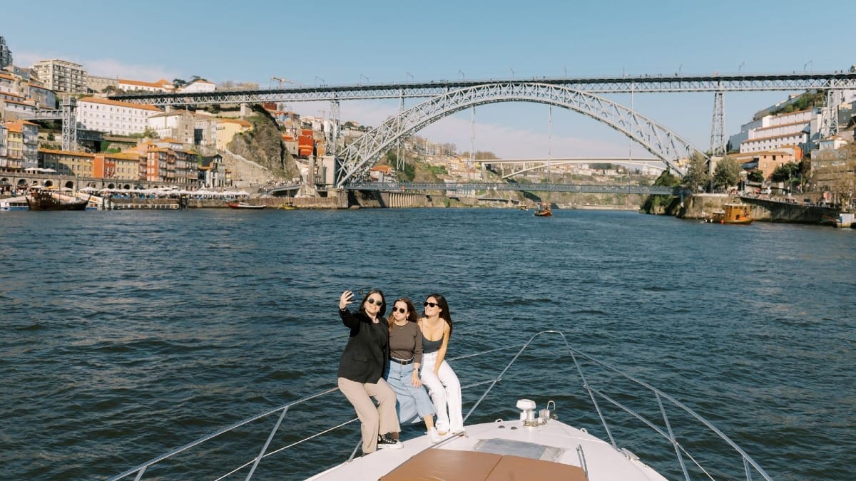 Invités prenant des photos à la proue du bateau avec la Ribeira, Gaia et le pont Dom Luís I en arrière‑plan