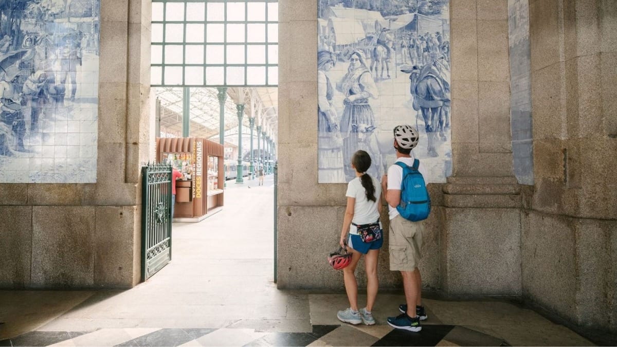 Cyclistes en visite à vélo électrique à Porto observant de près les superbes panneaux d'azulejos de la gare de São Bento