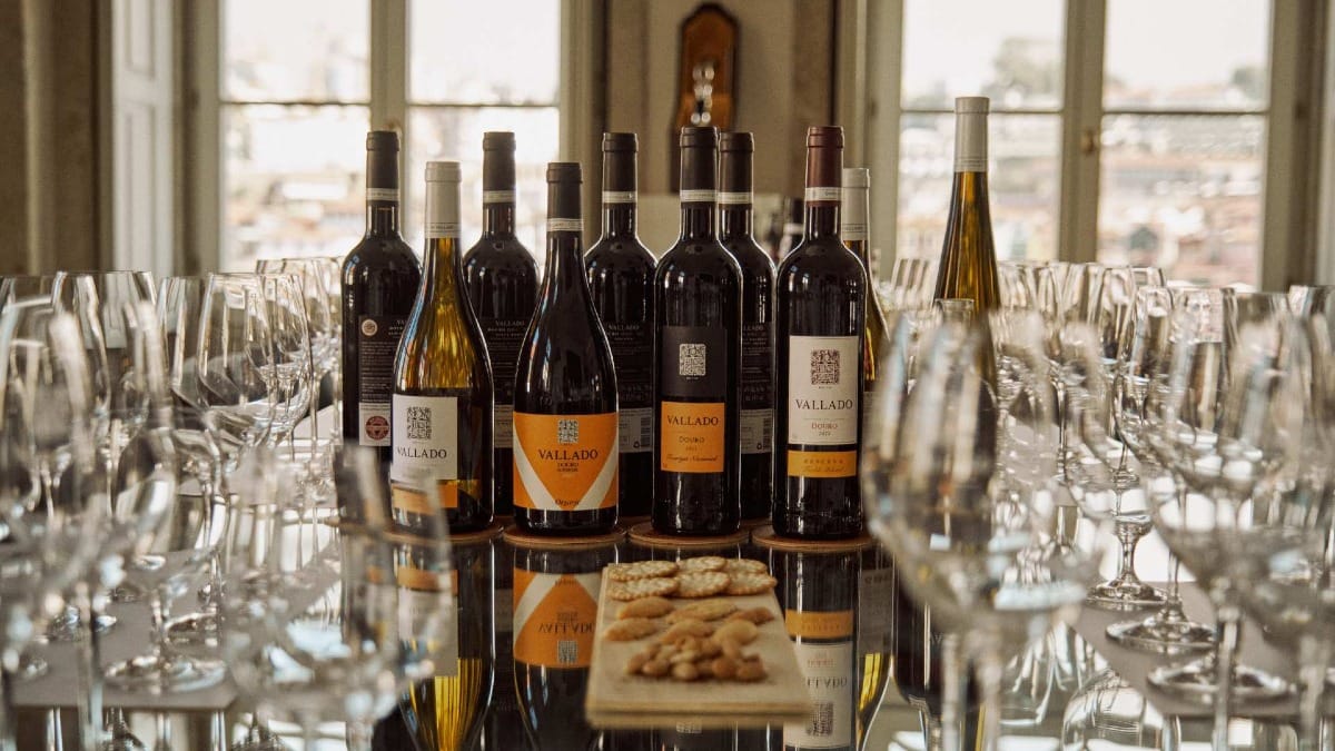 Mesa de prova com vinhos Vallado, copos e petiscos numa sala espelhada com luz natural