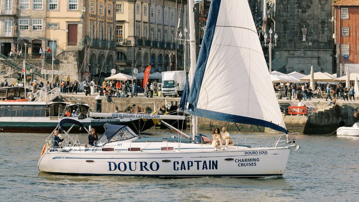 Private boat with open sail enjoying a wind ride in front of Ribeira, Porto’s historic district