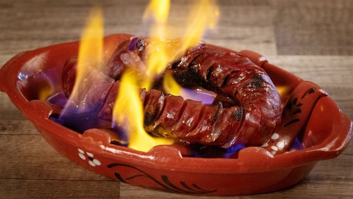 Chouriço português flambado servido num prato de barro durante uma prova gastronómica no Algarve