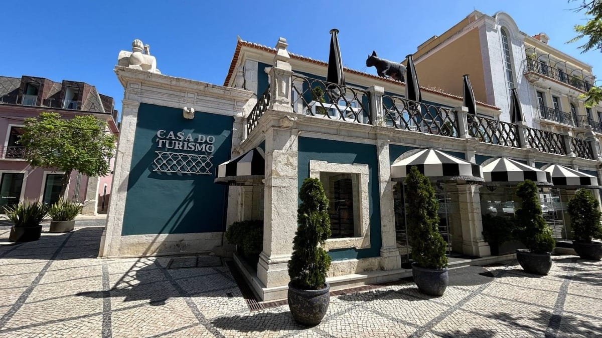 Casa do Turismo building in Setúbal with teal walls, black-and-white awnings, and statue of Bocage