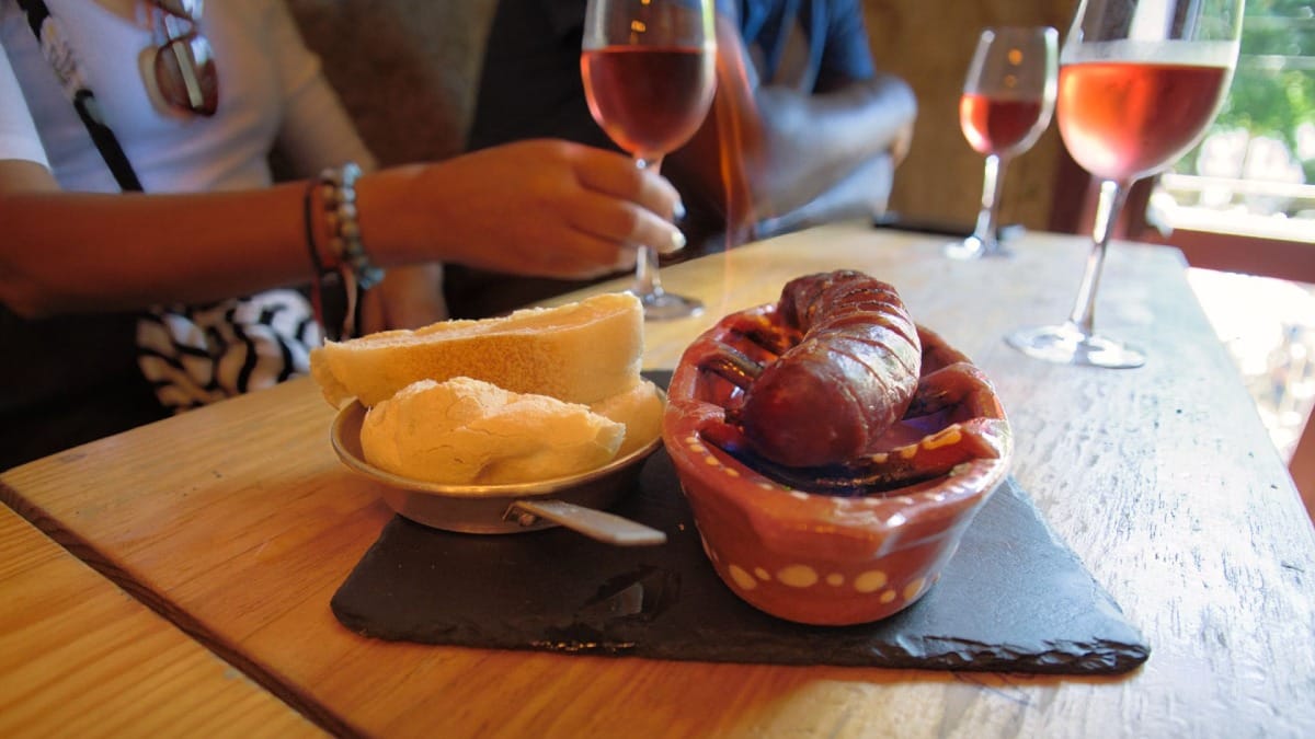 Chorizo tradicional flameado servido con pan y vino rosado en un wine bar de Oporto