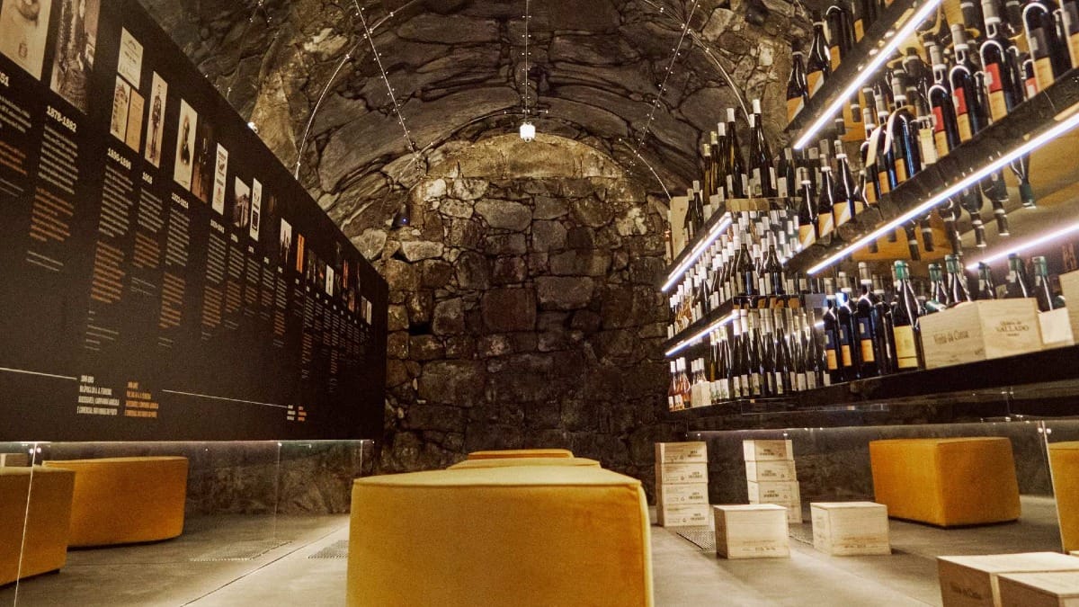 View of a stone-walled wine shop with bottles and history panels at Quinta do Vallado Porto
