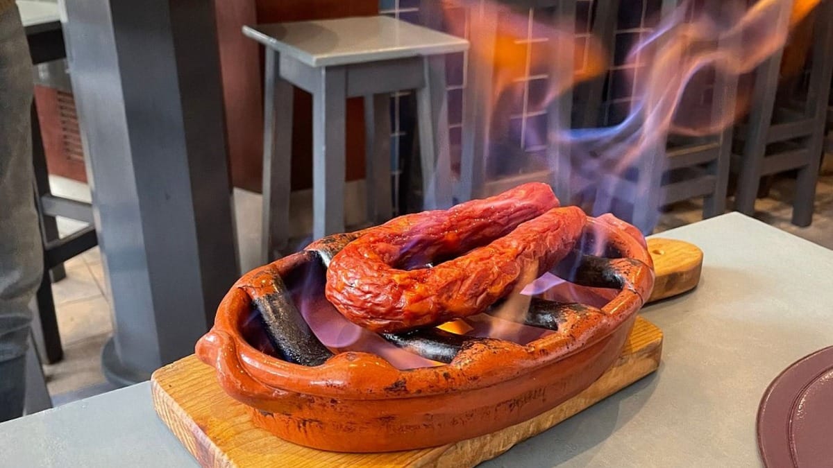 Chouriço portugais flambé, servi dans un plat en terre cuite pendant le Lagos Food Tour