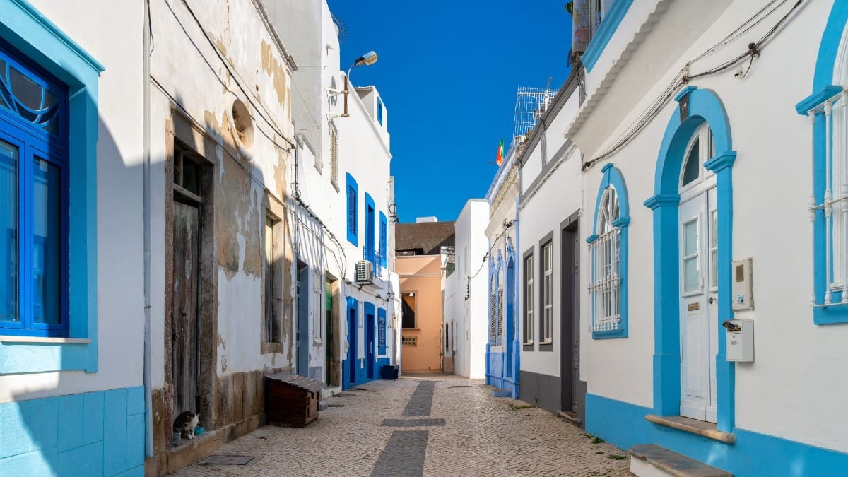 Rua estreita e empedrada em Olhão com casas caiadas e detalhes em azulejo