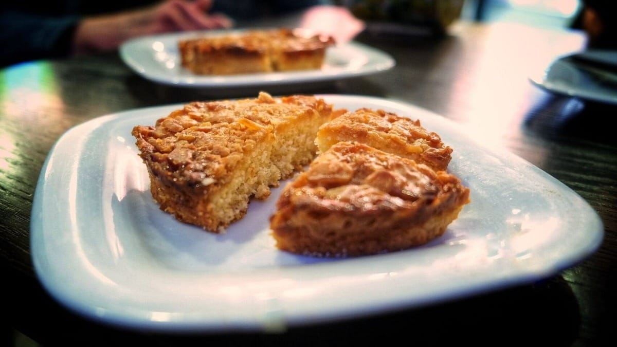 Fatias de tarte de amêndoa caseira servidas num prato branco durante a paragem da sobremesa em Lagos