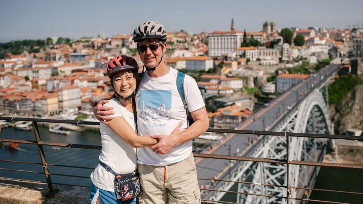 Couple capturing a photo at Serra do Pilar viewpoint with Porto, the Douro River, and Dom Luís I Bridge in the background