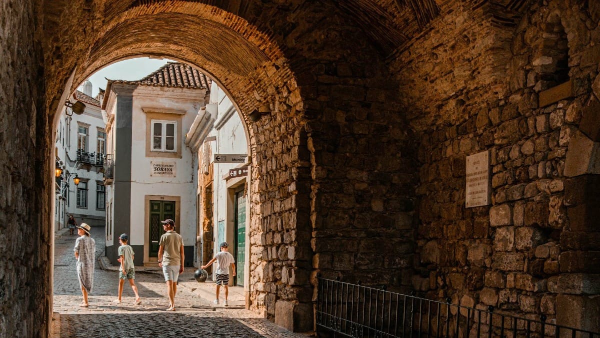 Familia caminando bajo un arco histórico en el casco antiguo de Faro durante una visita guiada