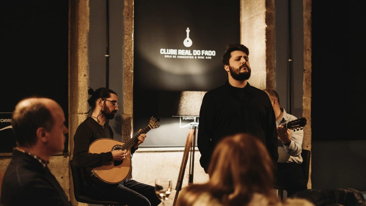 Chanteur de Fado et musiciens jouant devant un public attentif dans un bar à vin de Porto