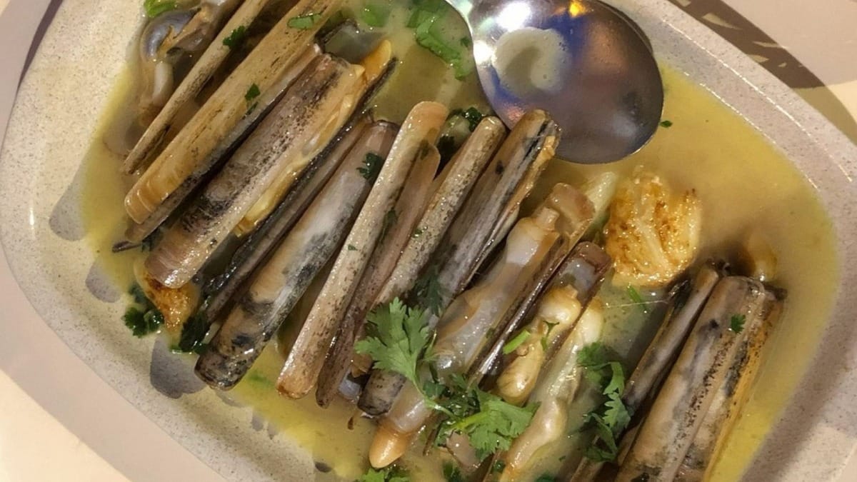 Navalhas grelhadas do Algarve servidas num prato branco com limão