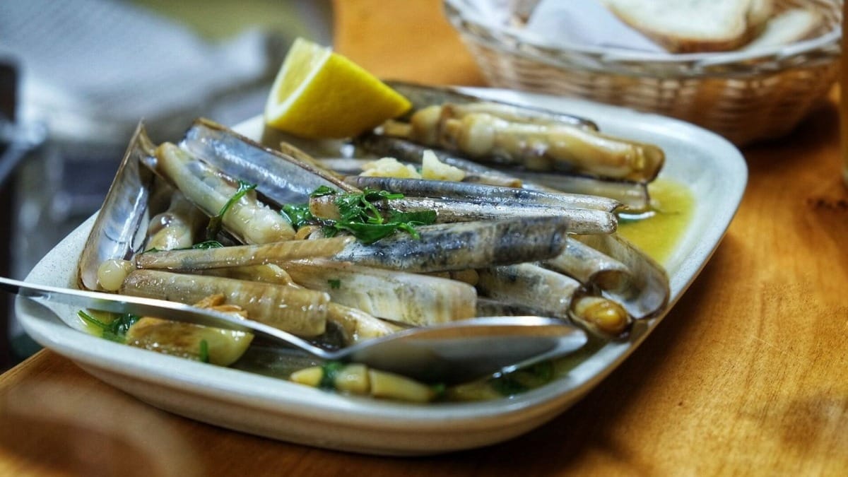 Couteaux à l’ail avec citron vert et persil frais, servis dans une assiette à Lagos