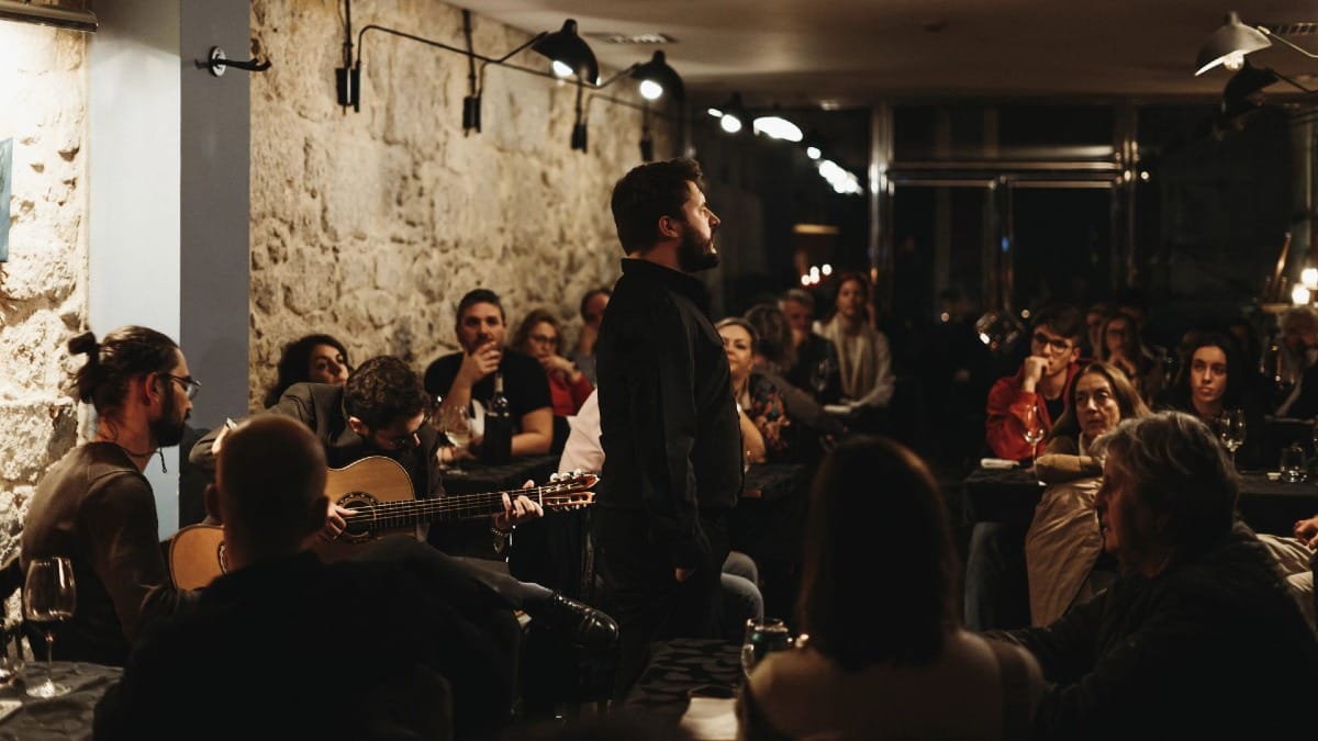 Chanteur de Fado interprétant en direct devant un public attentif dans un restaurant local à Porto