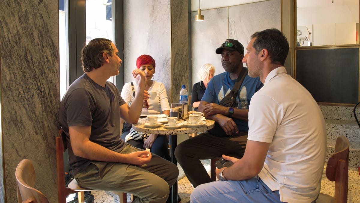 Travelers enjoying coffee and conversation at a traditional cafƩ in Porto during a Cooltour Oporto experience