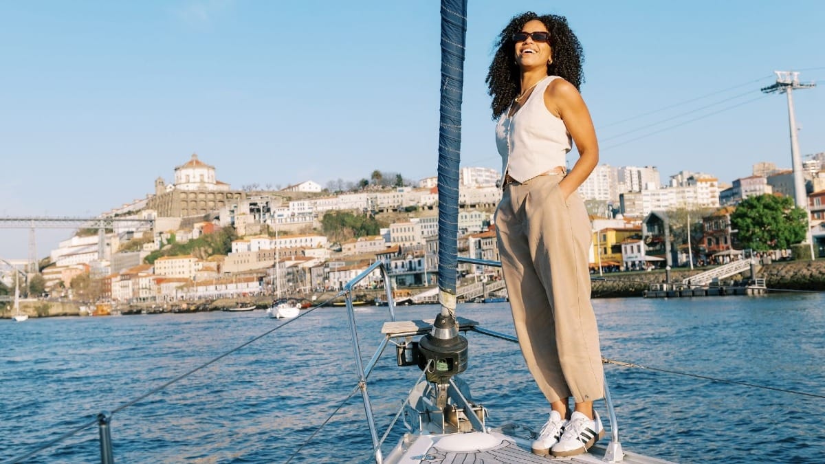 Invitado relajándose en la proa durante un tour en barco en Oporto, con Gaia y las bodegas de vino de Oporto al fondo