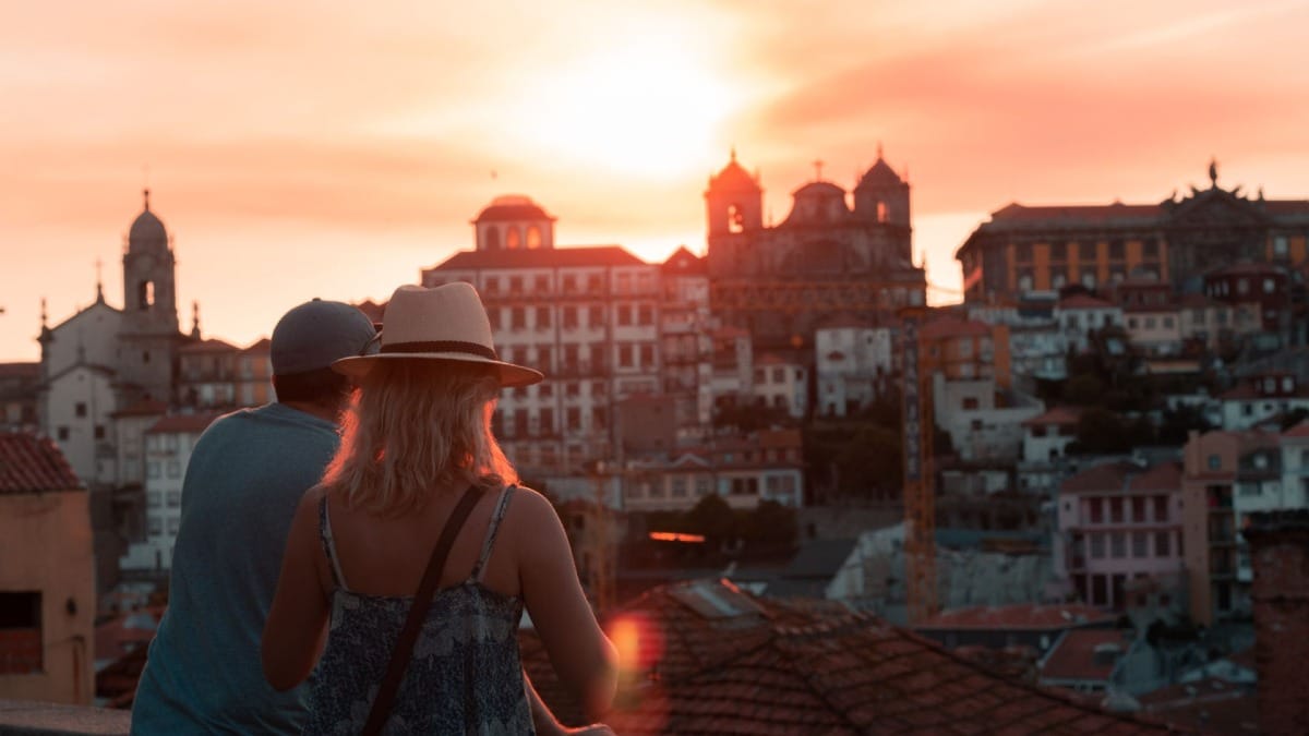Casal apreciando o pôr do sol sobre o centro histórico do Porto durante um tour de vinhos e Fado