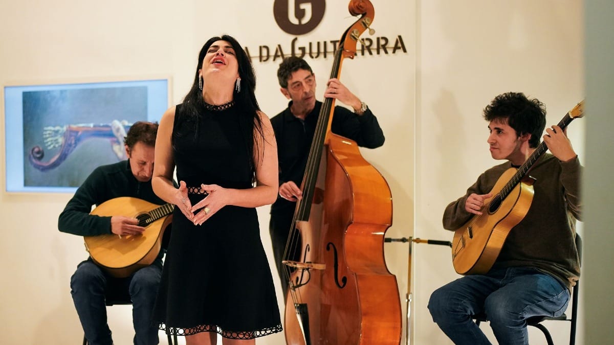 Fado singer performing on stage with passion alongside musicians at Casa da Guitarra in Porto