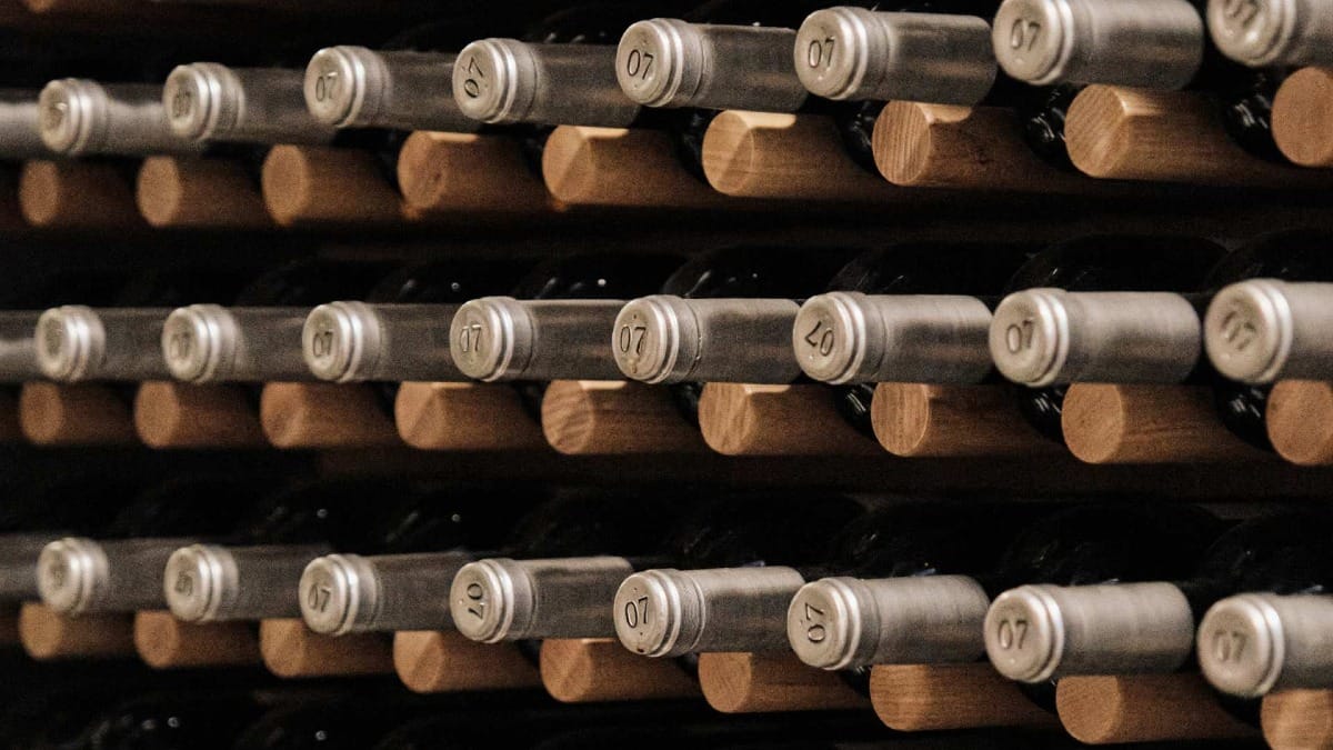 Garrafas de vinhos do Vale do Douro armazenadas horizontalmente numa garrafeira com marcações vintage