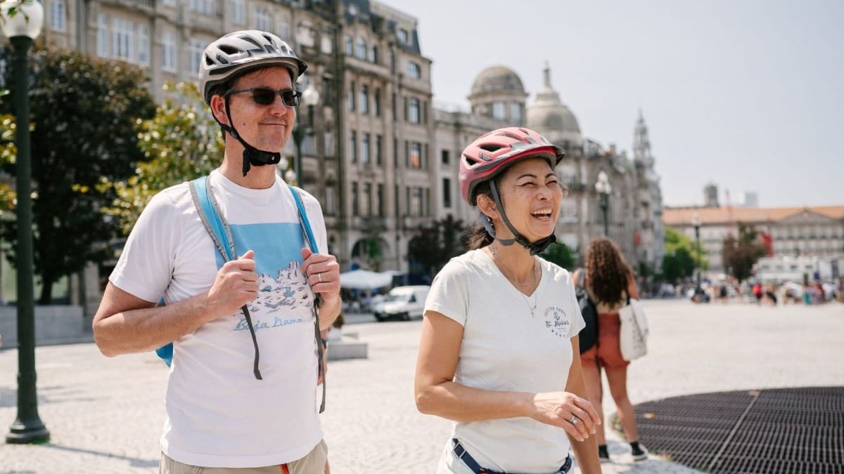 Couple souriant profitant de l’Avenida dos Aliados lors d'une visite à vélo électrique des incontournables de Porto