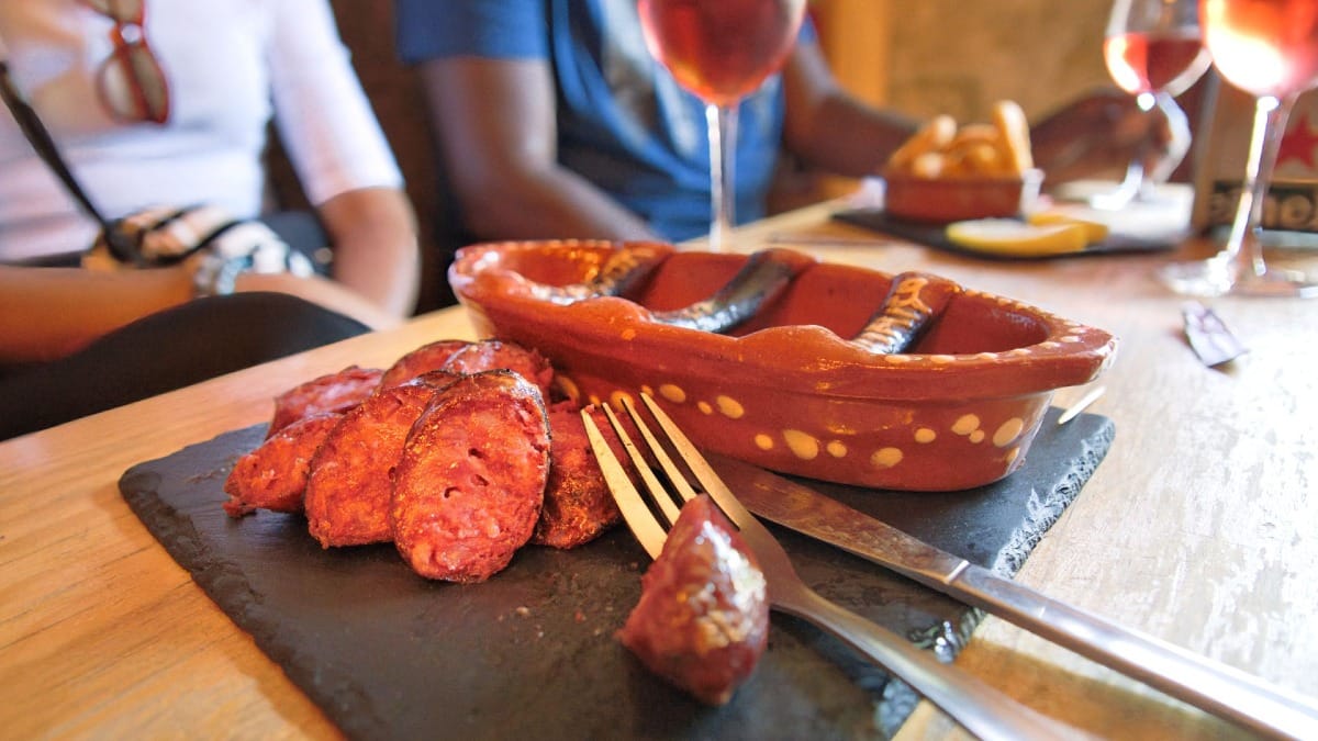 Gros plan de chorizo portugais grillé fraîchement tranché après avoir été flambé dans un plat en terre cuite
