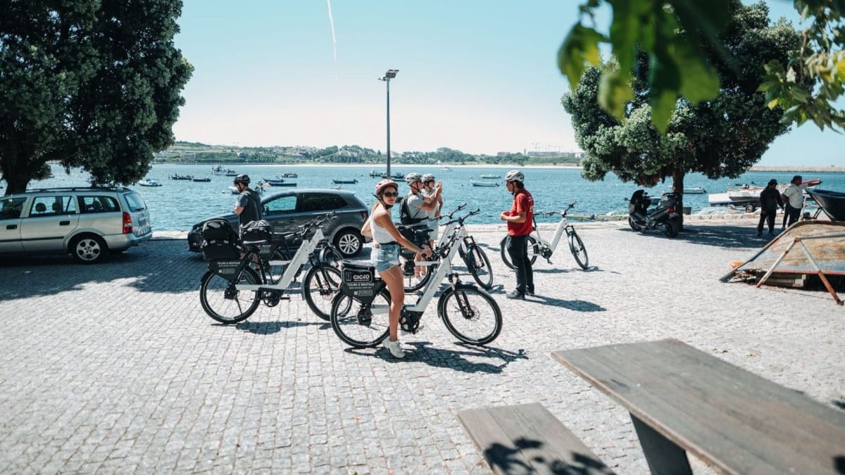 Small group stopping by Porto’s iconic riverfront with beautiful views of the Douro River and traditional fishing boats during an electric bike tour