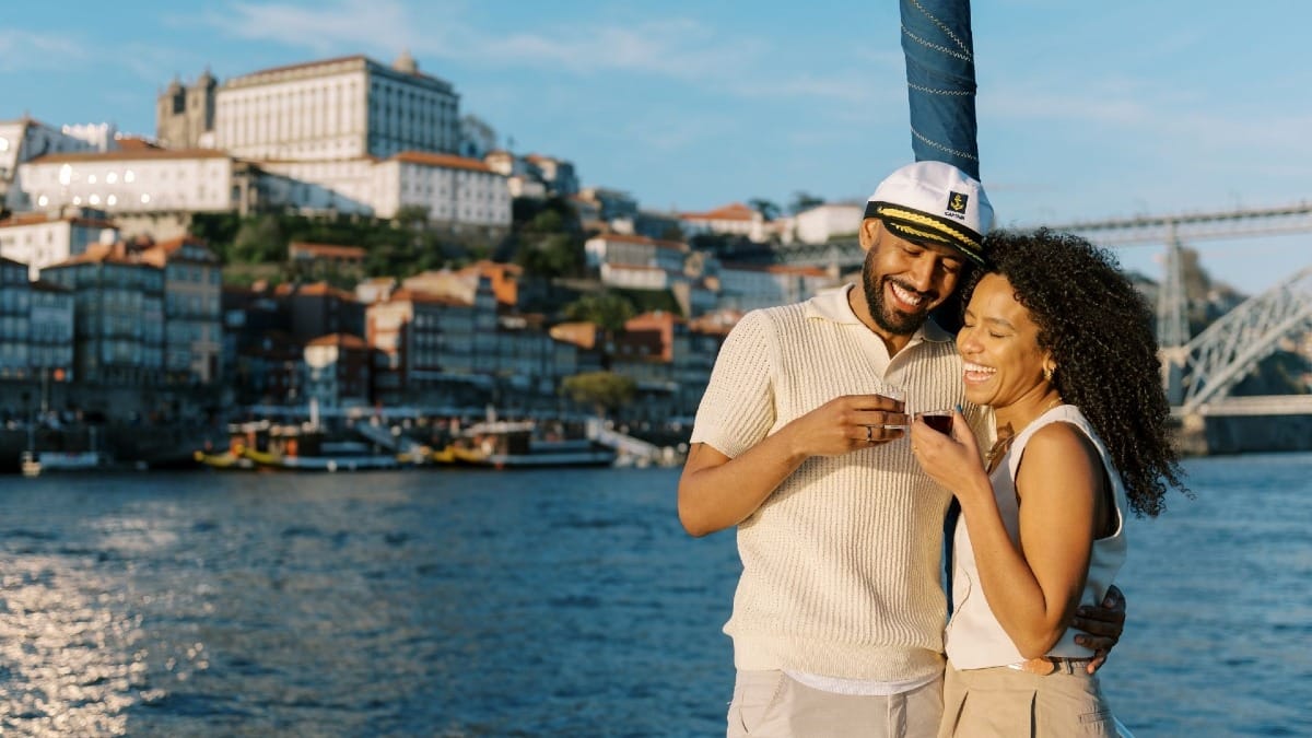 Couple trinquant avec une boisson de bienvenue à la proue lors d’une croisière de jour à Porto