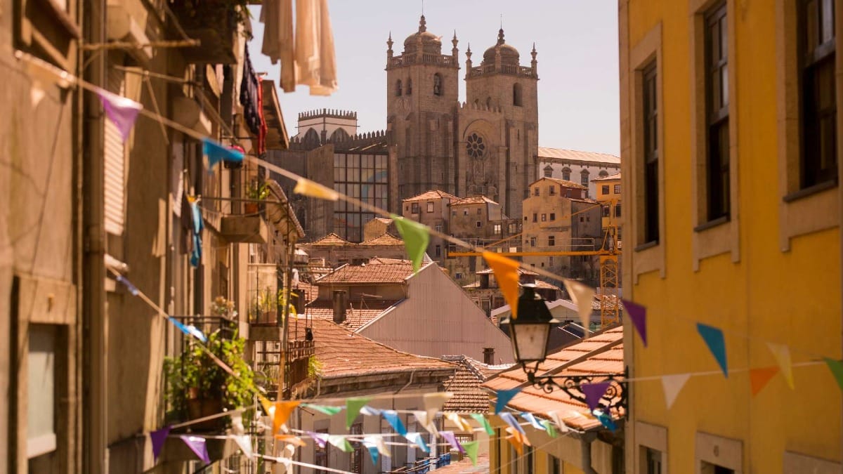 Promenez-vous dans les rues traditionnelles de Porto, où la vie quotidienne et les couleurs des festivals encadrent la cathédrale au-dessus des toits.