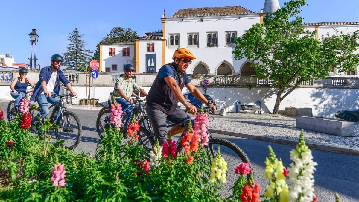 Pasando en bicicleta por el emblemático Palacio Nacional de Sintra durante la excursión en bicicleta eléctrica de Lisboa a Sintra.
