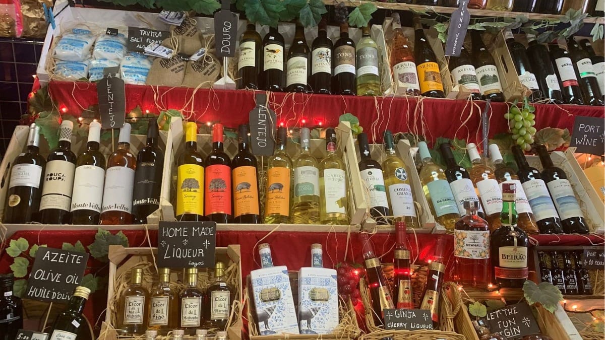 Estantes coloridos con vinos portugueses regionales, aceite de oliva y licores caseros en el mercado de Lagos