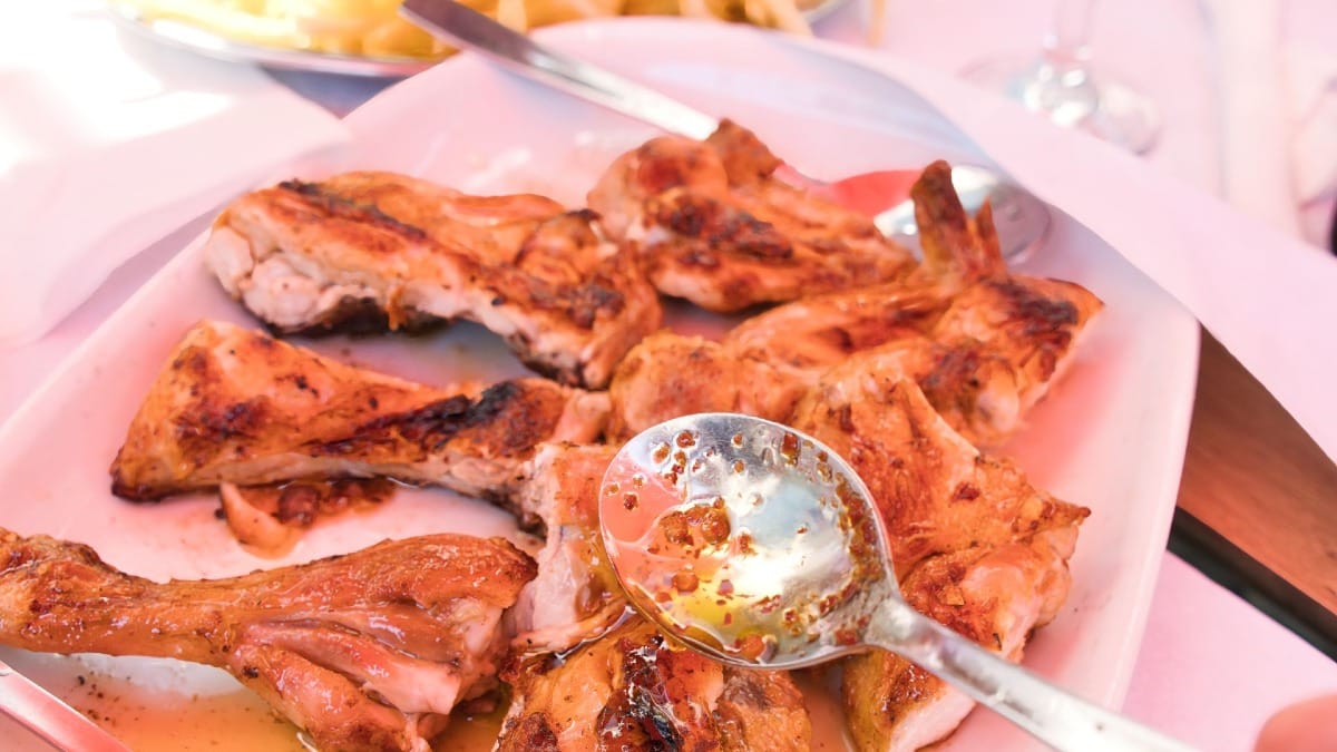 Spicy piri-piri chicken served with hot oil and crispy skin at a traditional local eatery in Porto