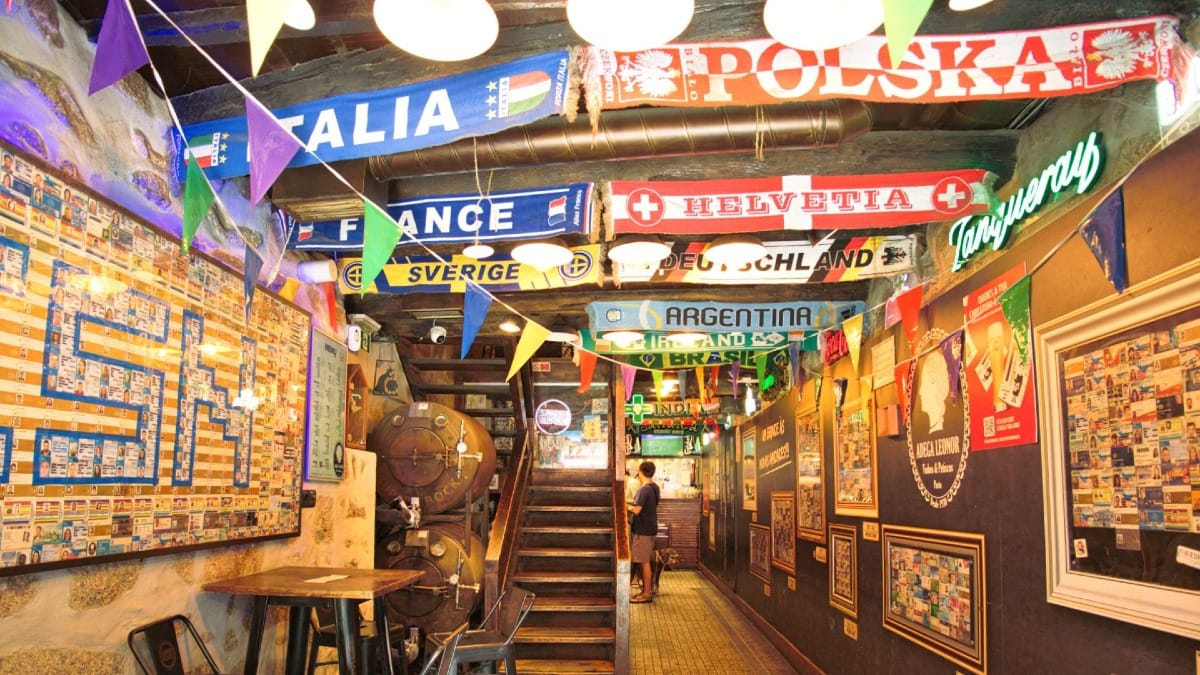Vibrant interior of a traditional Porto tavern decorated with football scarves from around the world, part of a Cooltour Oporto food tour route
