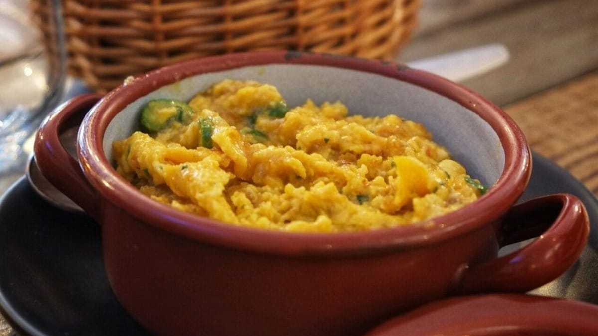 Plato de migas al estilo del Algarve con verduras, servido en cuenco de barro rojo