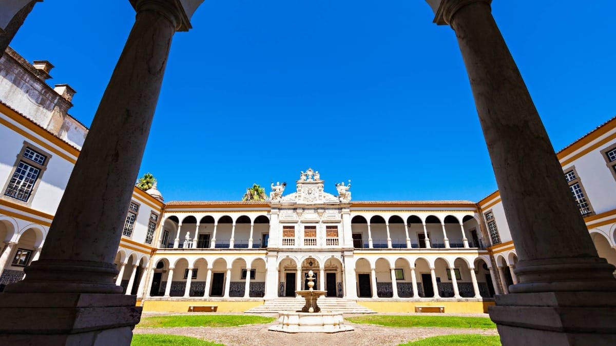 El tranquilo atrio de la Universidad de Évora, donde una fuente central completa este sereno claustro histórico.