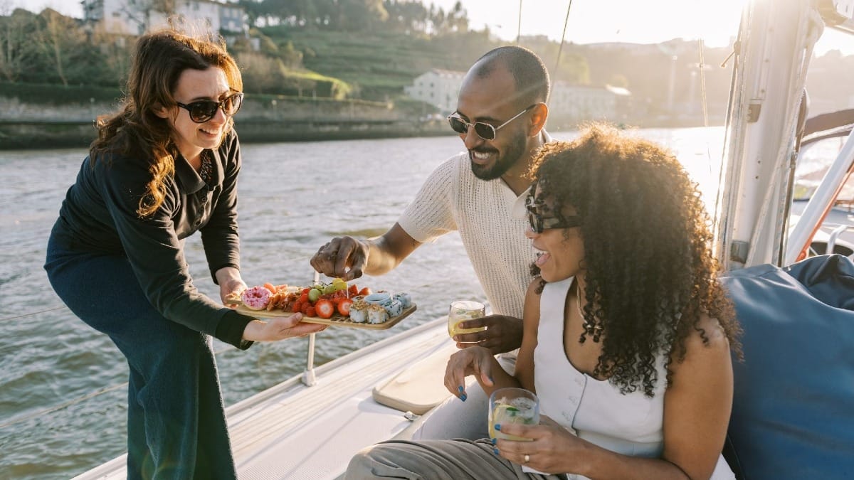 Invités dégustant des boissons de bienvenue servies par le skipper lors d'une excursion en bateau au coucher du soleil à Porto, Portugal