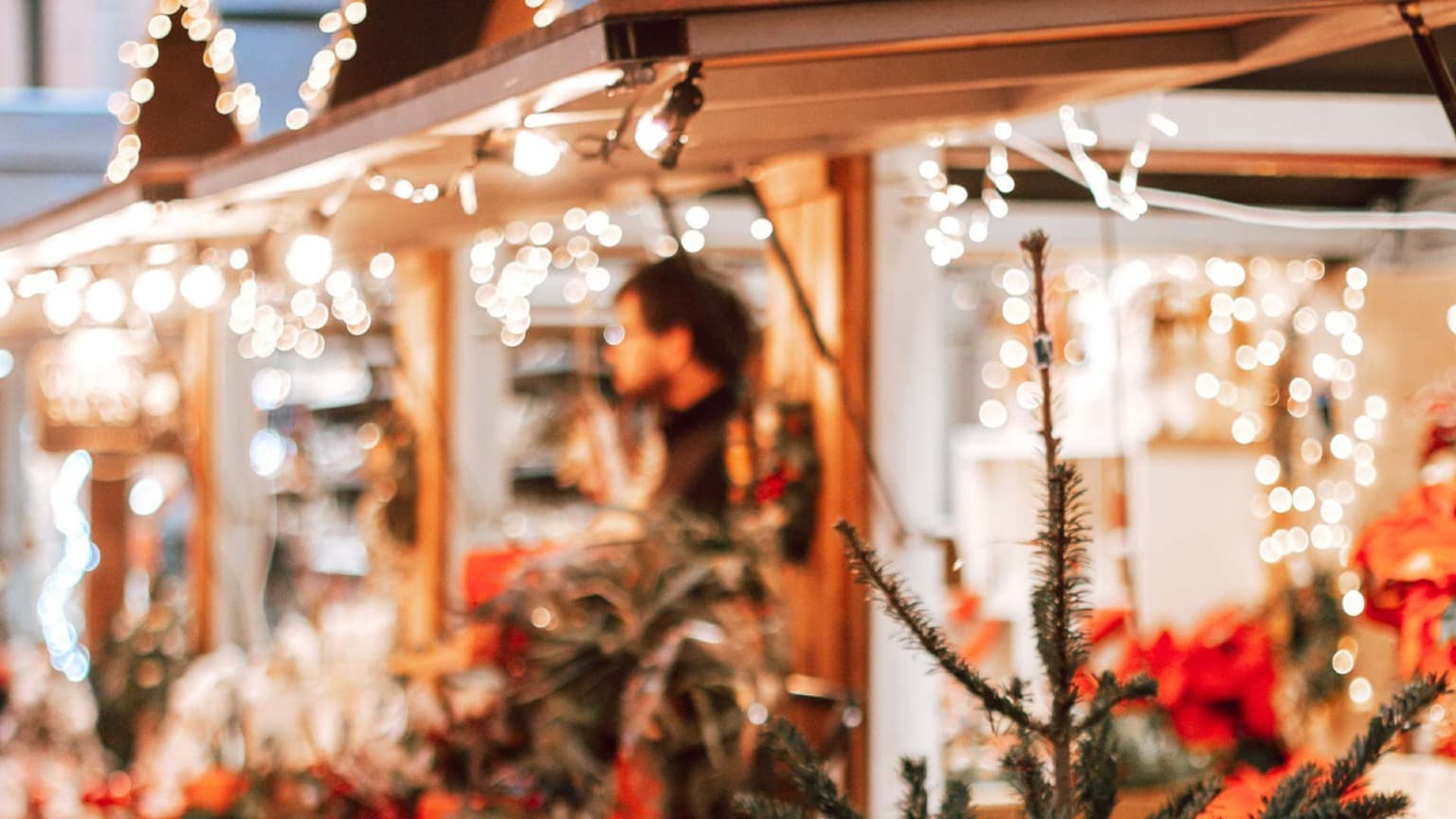 Primer plano de un puesto del mercado navideño de Oporto decorado con cálidas luces y adornos festivos.