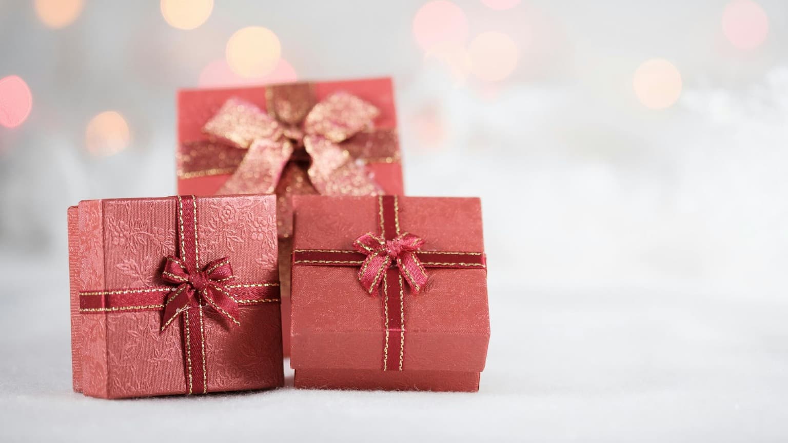 Trois cadeaux emballés avec des lumières festives en arrière-plan, mettant en évidence les achats de Noël à Porto.