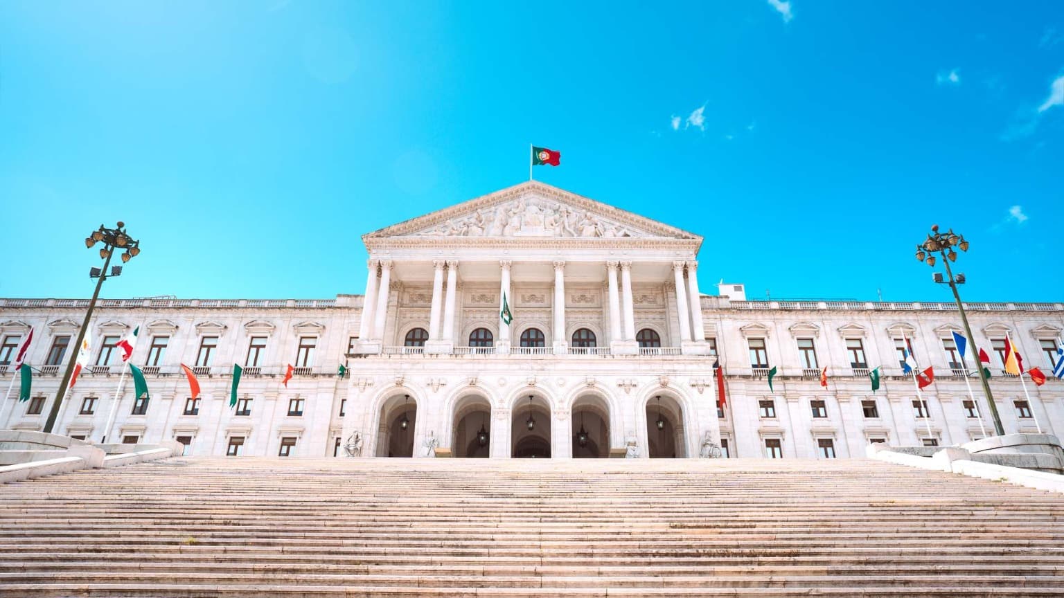 Edifício da Assembleia da República em Lisboa, Portugal, com a bandeira portuguesa hasteada sobre o parlamento nacional