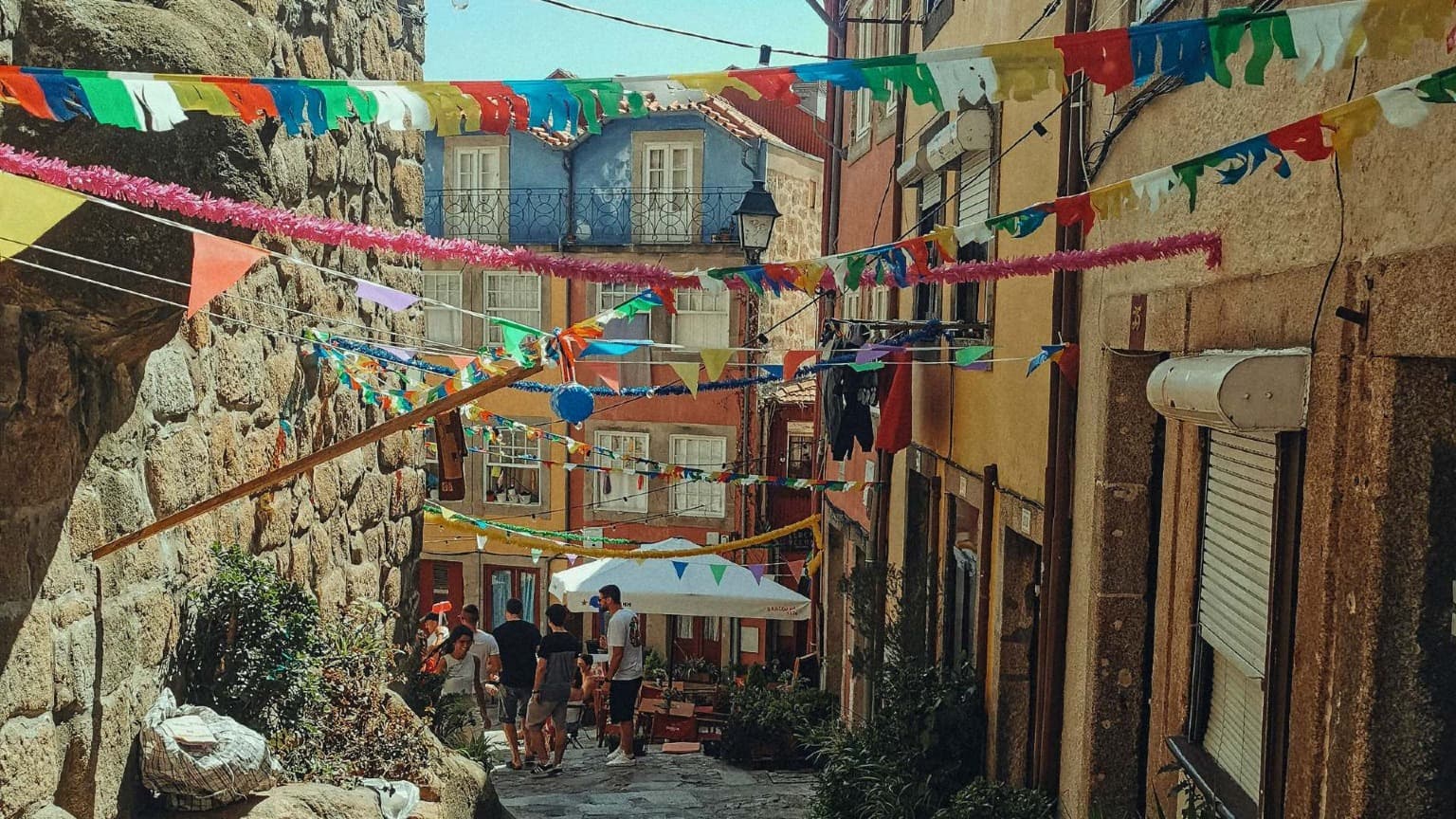 Bandeirinhas coloridas e decorações festivas penduradas numa rua histórica do Porto durante as Festas de São João