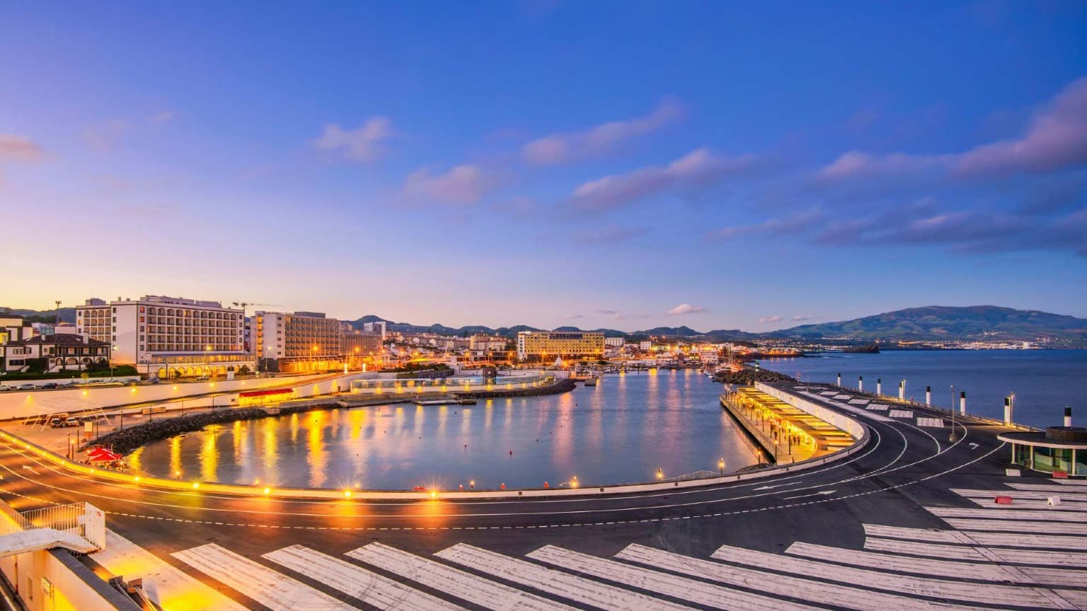 Vue nocturne de la marina de Ponta Delgada avec les lumières du front de mer se reflétant sur l'eau de l'île de São Miguel.