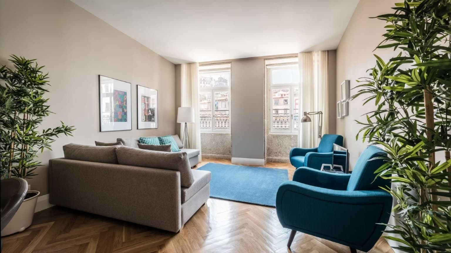 Salon élégant baigné de lumière naturelle et offrant une vue sur la ville dans les appartements Mouzinho 160, situés dans le quartier classé au patrimoine mondial de l'UNESCO à Porto.